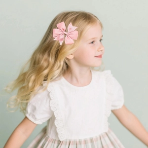 Pink grosgrain ribbon hair bow clip worn by a young girl for a sweet and stylish daily look