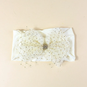 Cute nylon baby headband with a large sequined mesh flower bow in cream and gold