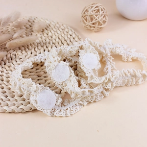 Trois bandeaux en dentelle au crochet élastique blanc cassé sur un tapis tissé
