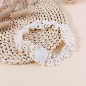 Bandeau bébé en dentelle crochetée fait main blanc crème sur un support tressé