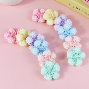 Colorful checkered fabric flower DIY accessories in soft macaron shades on pink background