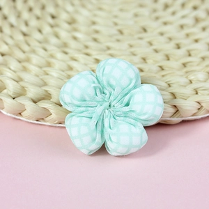Macro detail of green checkered fabric flower accessory for DIY sewing and hair crafts