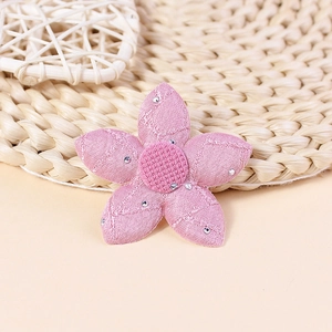 Macro view of pink embroidered five-petal flower patch with shiny silver rhinestones