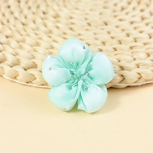 Macro detail of mint green satin fabric flower with sparkling rhinestones for hair accessories