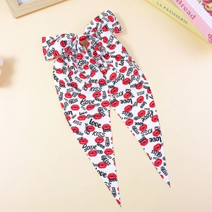 Dettaglio del fiocco per capelli in raso bianco con stampe di labbra rosse e scritte
