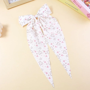 Dettaglio di un lungo fiocco per capelli in chiffon bianco con cuori rosa e stelle