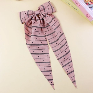 Detail of pink bow hair clip with black polka dots and wavy stripes on long ribbons