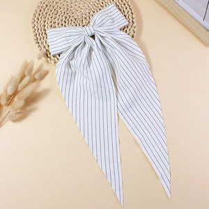 Detail of large striped bow hair clip with long ribbons on natural woven mat