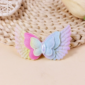 Close-up of glitter fabric angel wings and butterfly accessories with a central teardrop gem