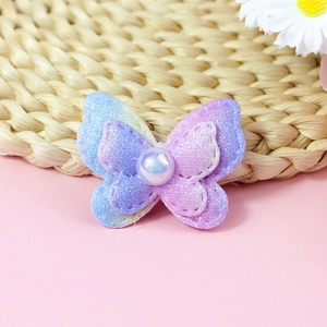 Close-up of double-layered gradient sequin butterfly accessory with central pearl