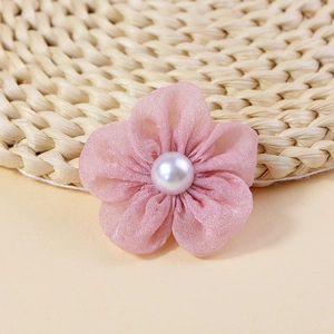 Detailed view of pink fabric flowers with central white faux pearl bead for DIY crafts