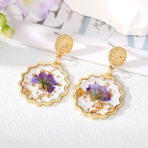 Elegant gold-framed round resin earrings with purple dried flowers and gold leaf accents