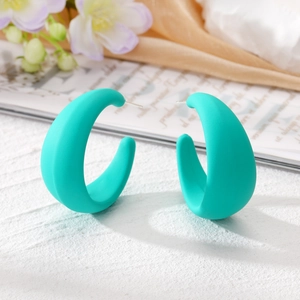 Boucles d'oreilles créoles C épaisses bleu turquoise mat sur fond texturé blanc moderne