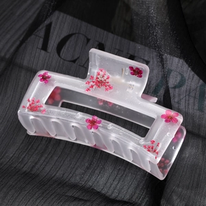 Rectangle matte resin hair claw with pink dried flowers on elegant black fabric background