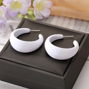 Gros plan de boucles d'oreilles créoles en C blanches sur boîte à bijoux en soie et fleurs