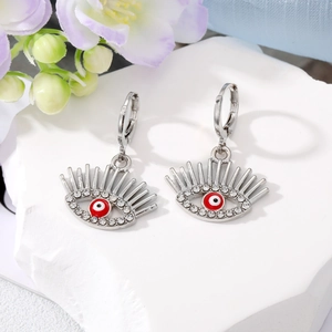 Détail de boucles d'oreilles œil du démon argentées avec pupilles rouges et cristaux