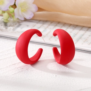 Boucles d'oreilles créoles C rouges épaisses au fini mat sur une surface texturée