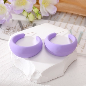 Détail des boucles d'oreilles créoles violettes en forme de C sur support en pierre