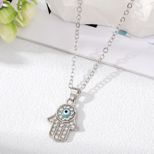 Dettaglio del ciondolo Mano di Hamsa argentato con strass brillanti e occhio blu centrale