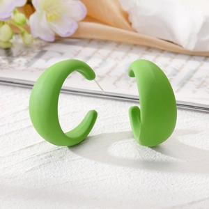 Boucles d'oreilles créoles C vert fruit mat sur un fond élégant de style de vie