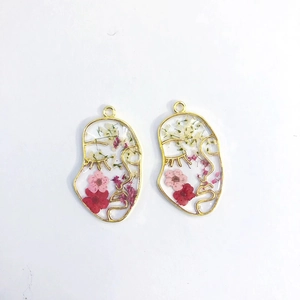 Close-up of golden face outline earrings with real dried flowers embedded in clear resin