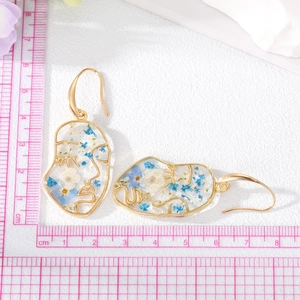 Golden face silhouette earrings with real blue and white dried flowers in clear resin