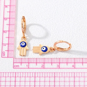 Detailed view of Hamsa Hand and Evil Eye gold earrings with ruler for size measurement