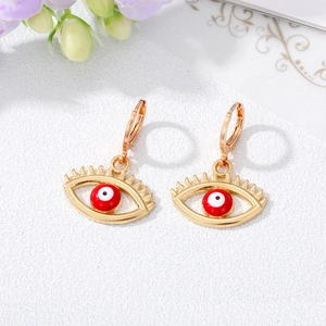 Retro evil eye earrings in gold finish with red crystal detail on white floral background