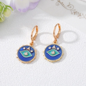 Detailaufnahme goldener Creolen mit blauem Emaille-Auge und glänzenden Zirkonia-Steinen