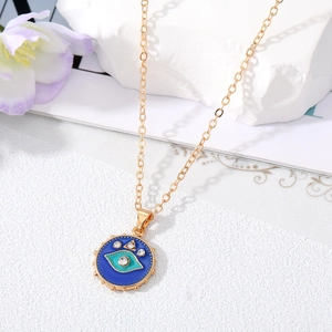 Goldene Halskette mit blauem Evil Eye Anhänger und funkelnden Kristallen auf Steinuntergrund
