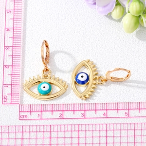 Detailed view of gold evil eye earrings with dimensions shown on a centimeter ruler