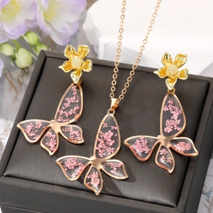 Parure di gioielli a farfalla dorata con fiori secchi rosa con collana e orecchini a perno