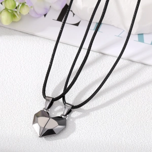 Detailed macro view of magnetic heart-shaped split pendants in polished dark gunmetal finish