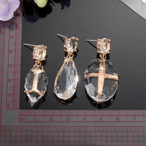 Trois boucles d'oreilles en cristal avec croix rose doré et gouttes sur fond noir