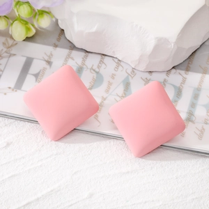 Pink matte square stud earrings in candy macaron tones on a stylish textured marble display