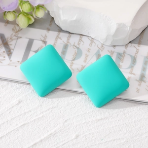 Close-up of mint green matte square stud earrings featuring a geometric block design