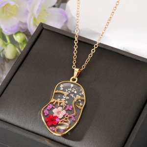 Artistic gold face silhouette necklace featuring colorful dried flowers in clear resin