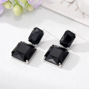 Detail of square black crystal earrings with silver claw setting on a white background