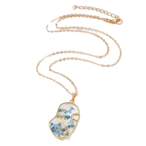 Artistic gold necklace with face-shaped pendant featuring blue dried flowers and gold foil