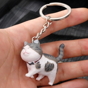 Cute grey and white striped kitten keychain with a red collar held in hand