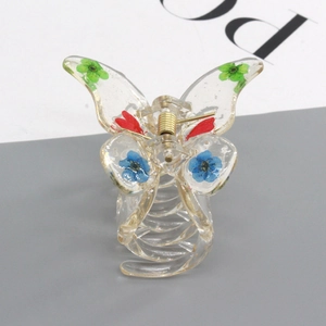 Detailed macro view of butterfly hair claw clip with colorful dried flowers and gold spring