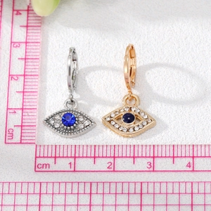Evil Eye Creolen mit Zirkonia-Besatz in Silber- und Goldtönen auf weißem strukturiertem Hintergrund
