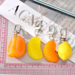Detailed view of realistic resin orange and lemon fruit pendants with silver metal clasps