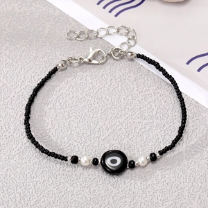 Detailed macro view of black seed bead bracelet featuring an evil eye charm and lobster clasp
