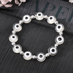 Détail du bracelet Evil Eye avec perles en acrylique blanc et entretoises argentées