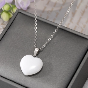 Detailed close-up of a smooth white stone heart pendant on a silver-tone metal chain