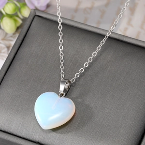 Detail of a heart-shaped opal pendant necklace on a refined grey jewelry display box