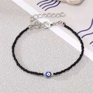 Detail of handmade beaded bracelet with blue evil eye charm and silver lobster clasp
