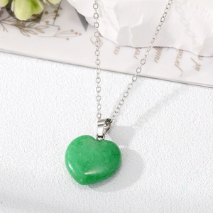 Green heart crystal pendant necklace with fine silver chain on a minimalist stone base