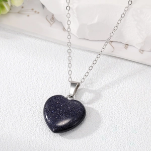 Detail of blue sandstone heart pendant on a silver metal chain over a white surface